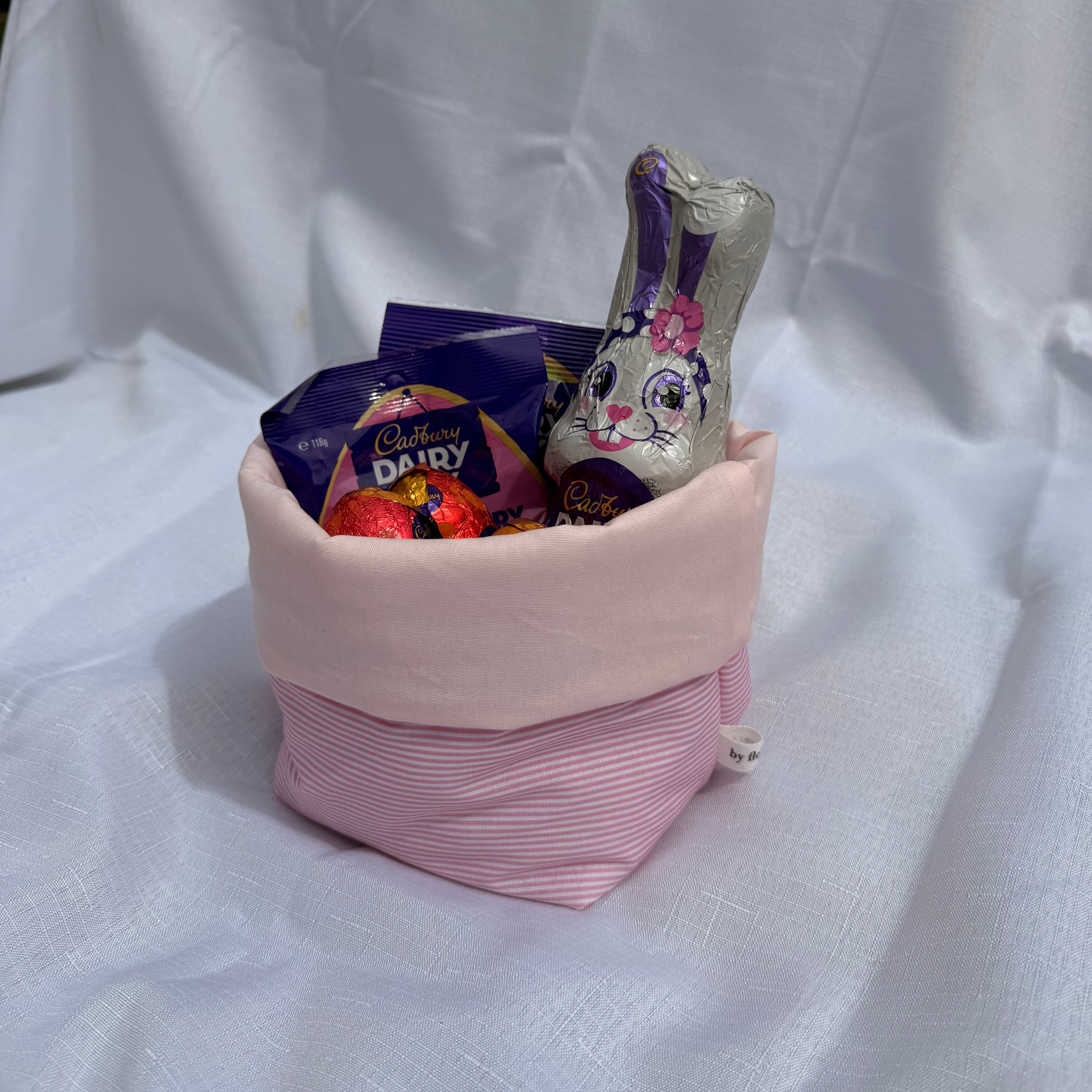 Pink fabric pouch with a floral-patterned bottle on a white background