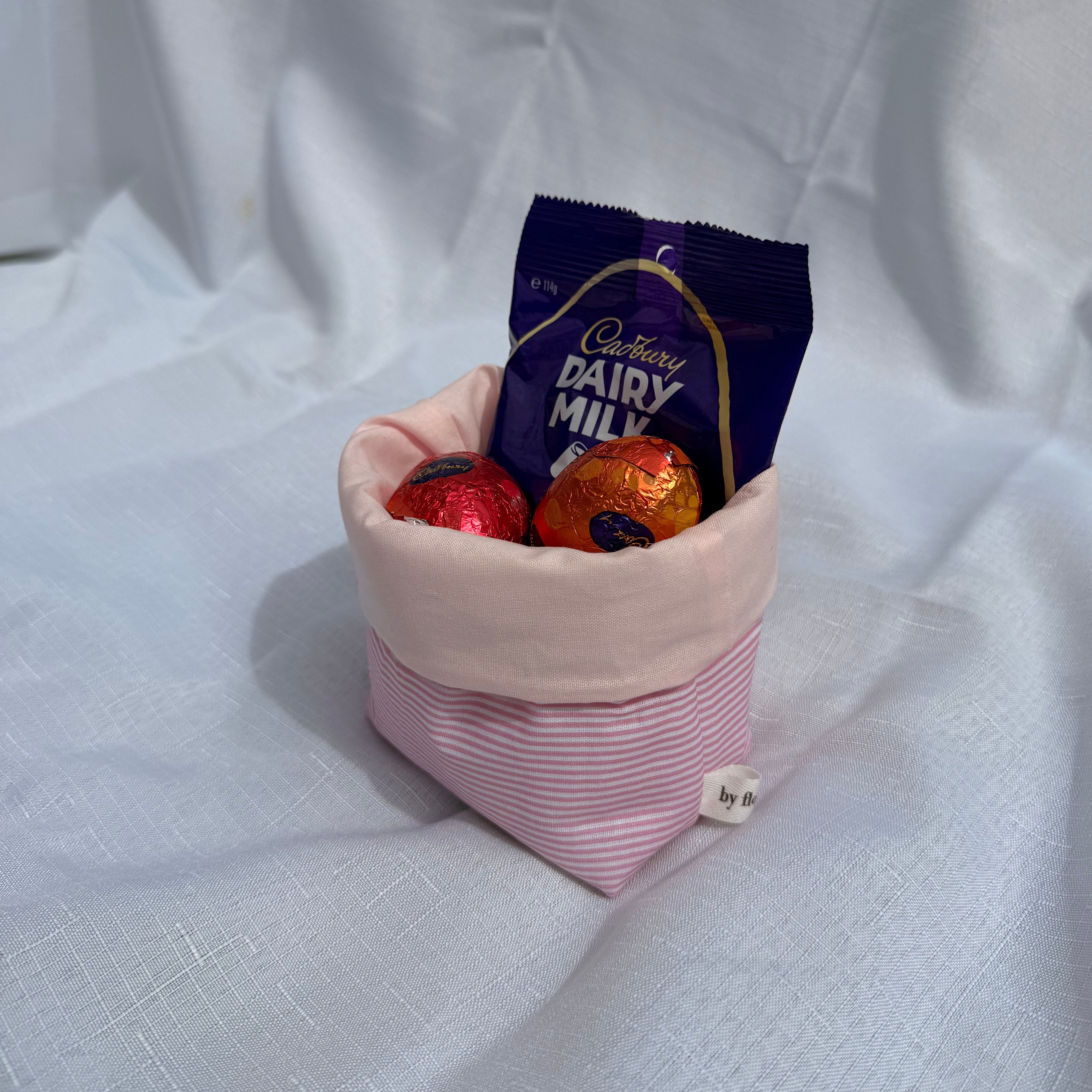 Pink fabric cone filled with chocolate bars on a white background