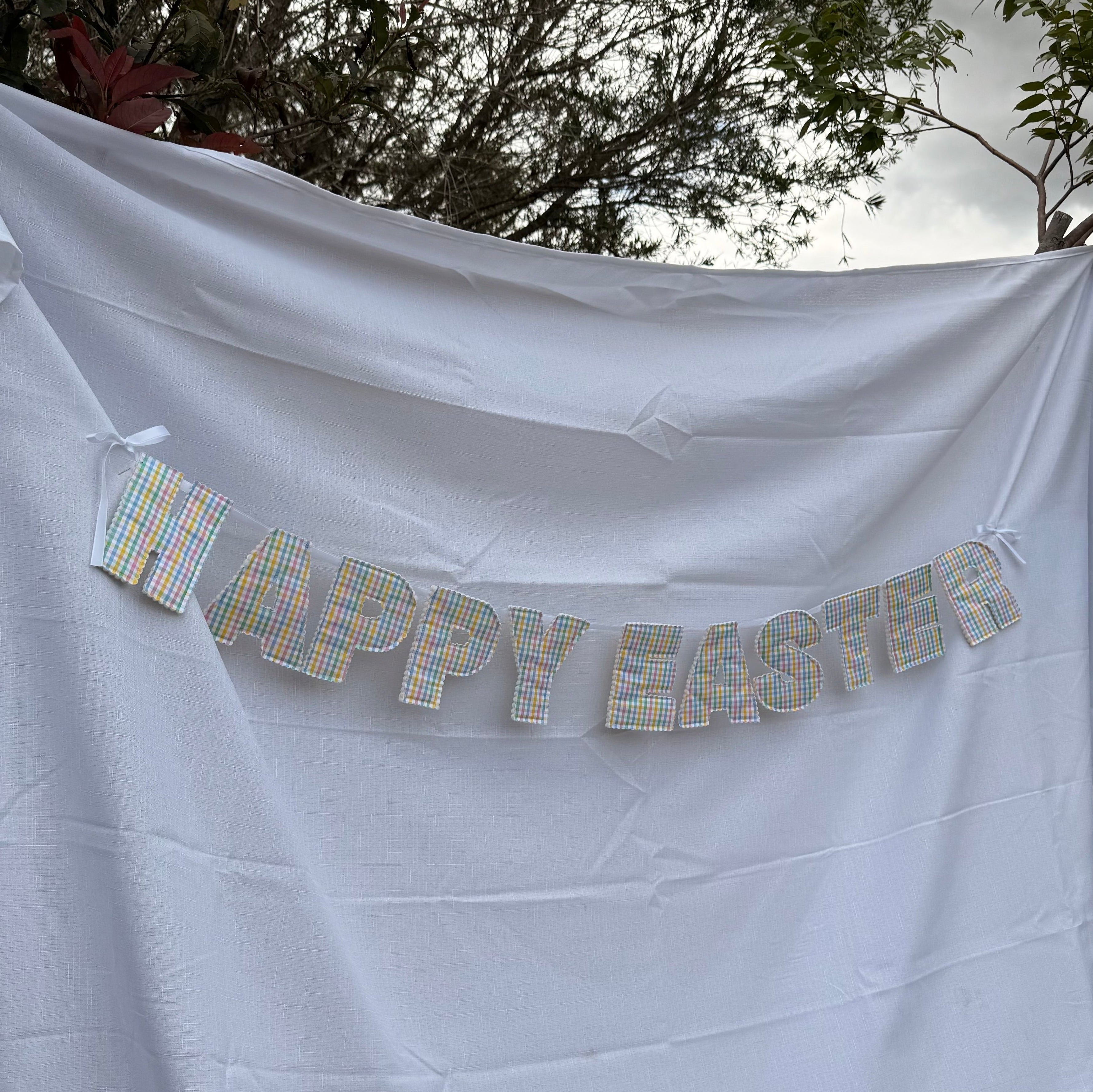 Happy Easter banner on a white sheet with trees in the background